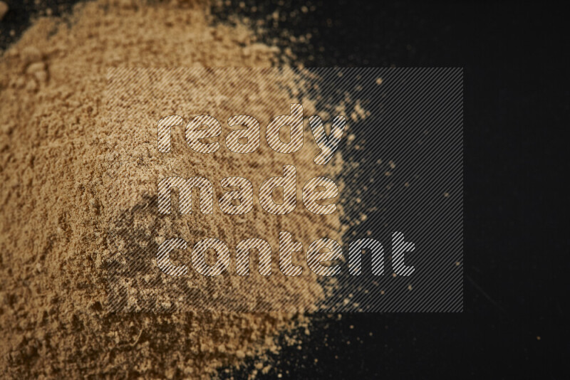 A bunch of ground ginger powder on black background