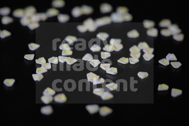 Colorful plastic shards for decoration scattered on a black background