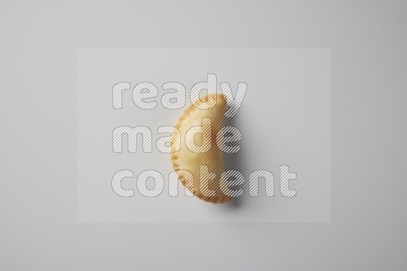 One fried sambosa from a top angle on a white background