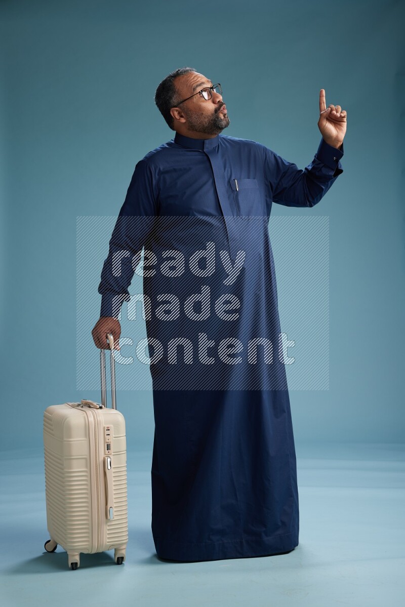Saudi Man without shimag Standing pulling travel bag on blue background