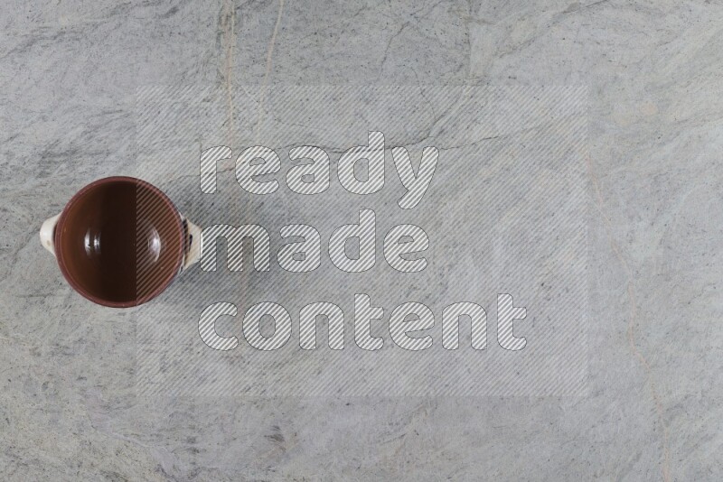 A multicolored pottery pot with its lid on grey marble background