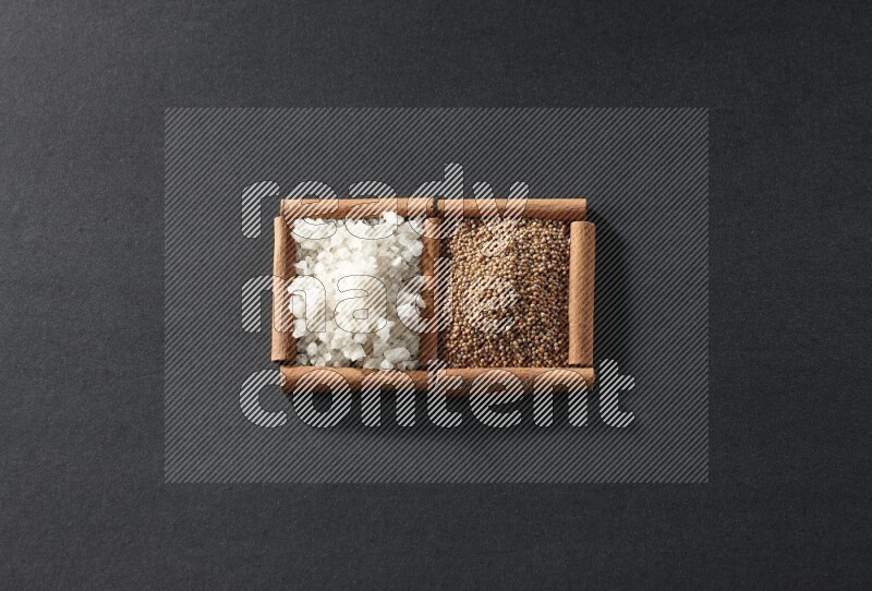 2 squares of cinnamon sticks full of mustard seeds and white salt on black flooring