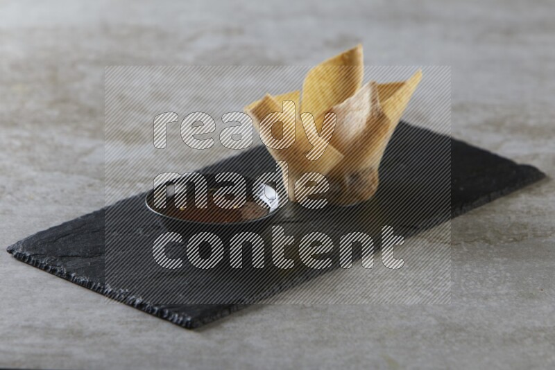 wonton cups with soy sauce ramkin on rectangle slate on grey textured counter top