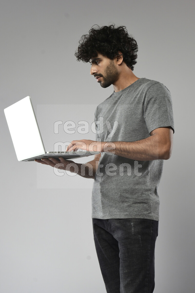 A man wearing casual standing and working on a laptop on white background