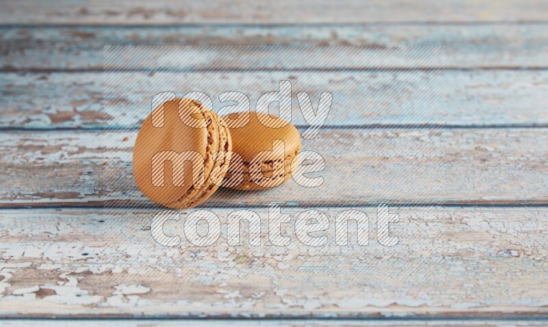 45º Shot of two Brown Maple Taffy macarons on light blue wooden background