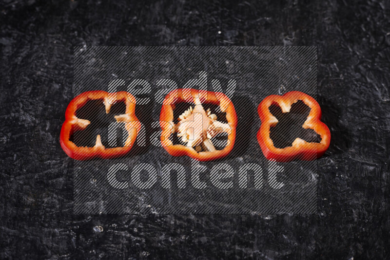 Red bell pepper slices on black background