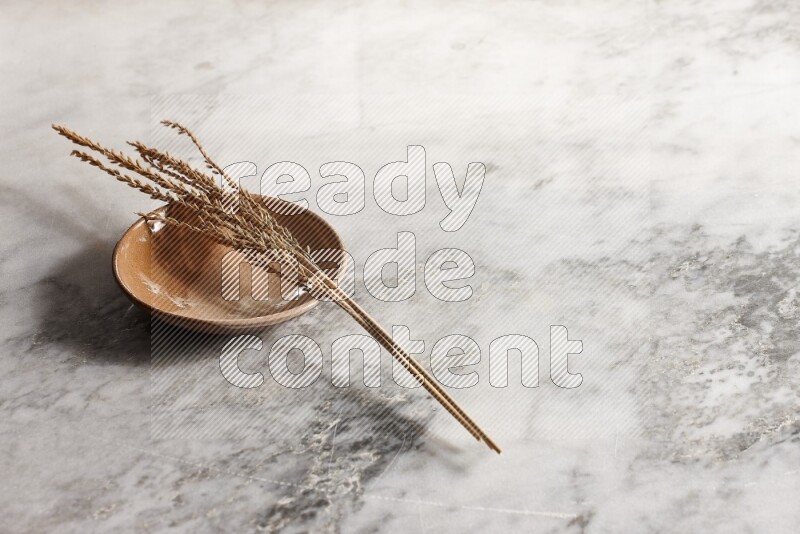 Wheat stalks on multicolored pottery plate on grey marble background