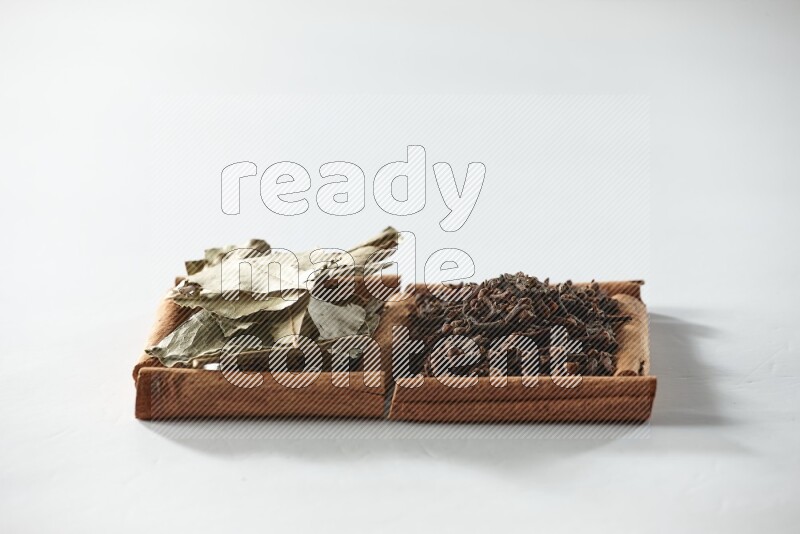 2 squares of cinnamon sticks full of cloves and bay laurel leaves on white flooring
