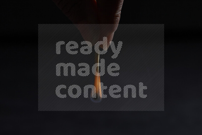 A burning matchstick isolated on dark backdrop