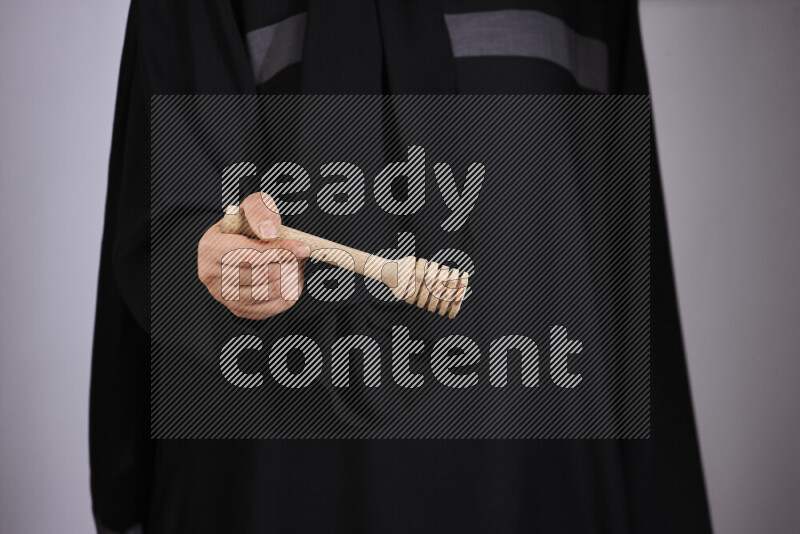 A woman in black abaya holding different wooden essentials in different positions
