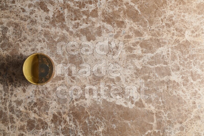 A multicolored pottery cup on beige marble background