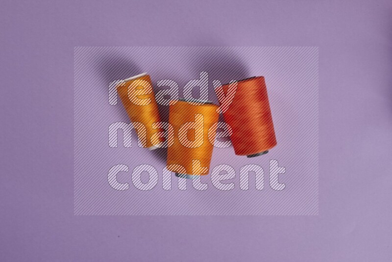 An orange collection of sewing and tailoring tools arranged on a purple background