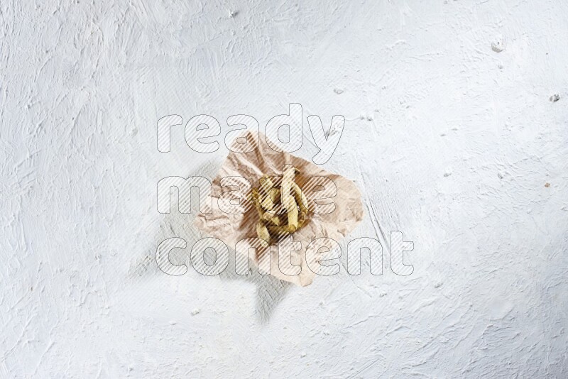 أصابع الكركم المجففة في قطعة من الورق على خلفية بيضاء