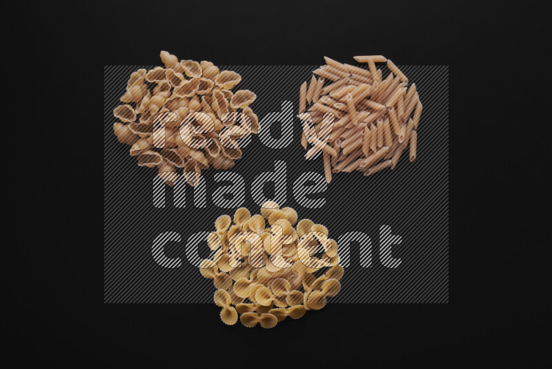 Different pasta types in bunches on black background