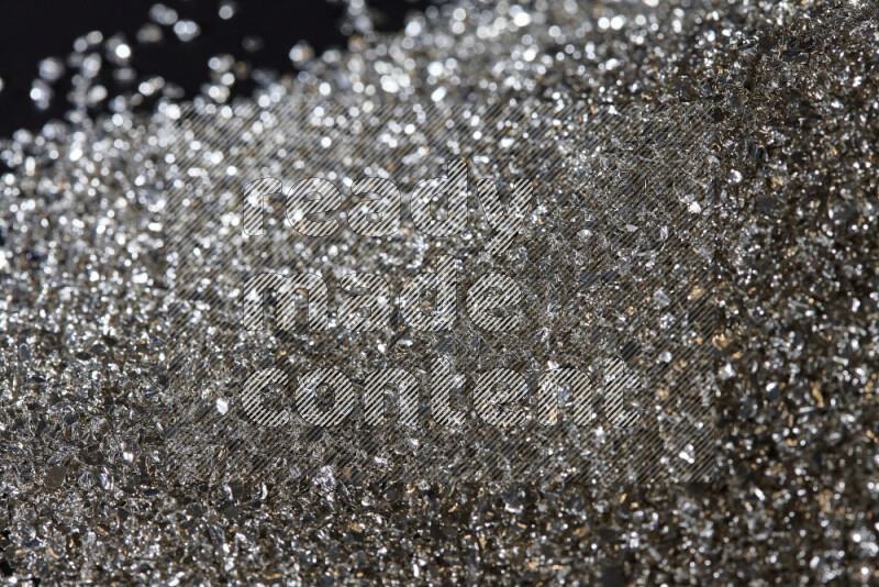 Silver shimmering fragments of glass scattered on a black background