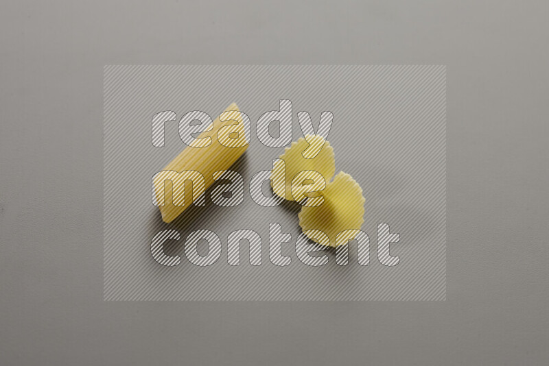 Penne pasta with other types of pasta on grey background
