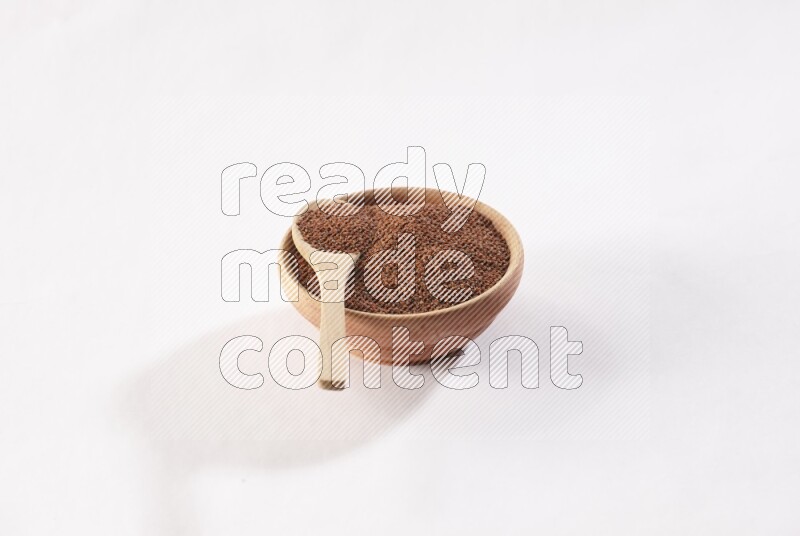 A wooden bowl and spoon full of garden cress seeds on a white flooring