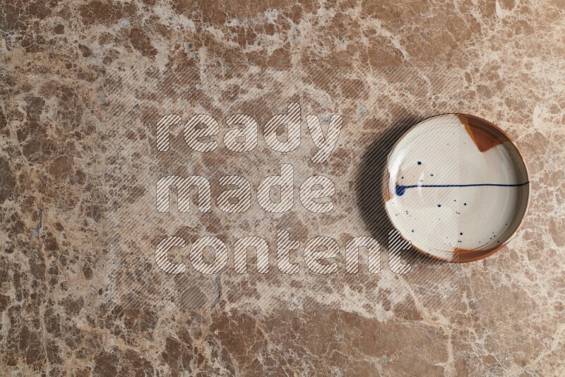 A multicolored pottery plate on beige marble background