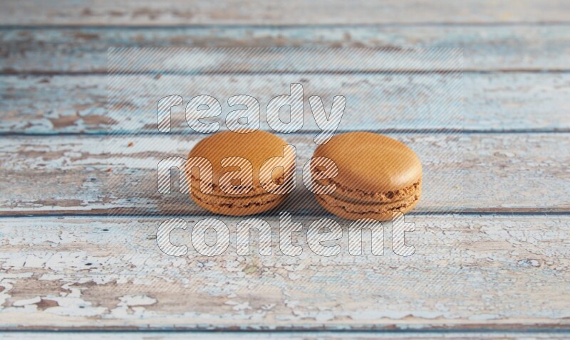 45º Shot of two Brown Maple Taffy macarons on light blue wooden background