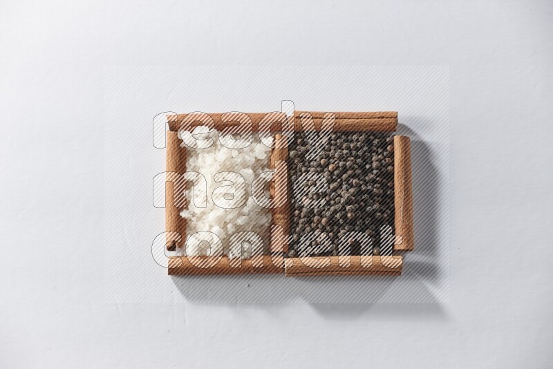 2 squares of cinnamon sticks full of black pepper and white salt on white flooring