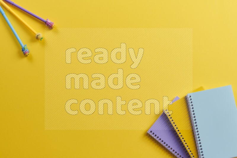 Multicolored notebooks with school supplies on yellow background