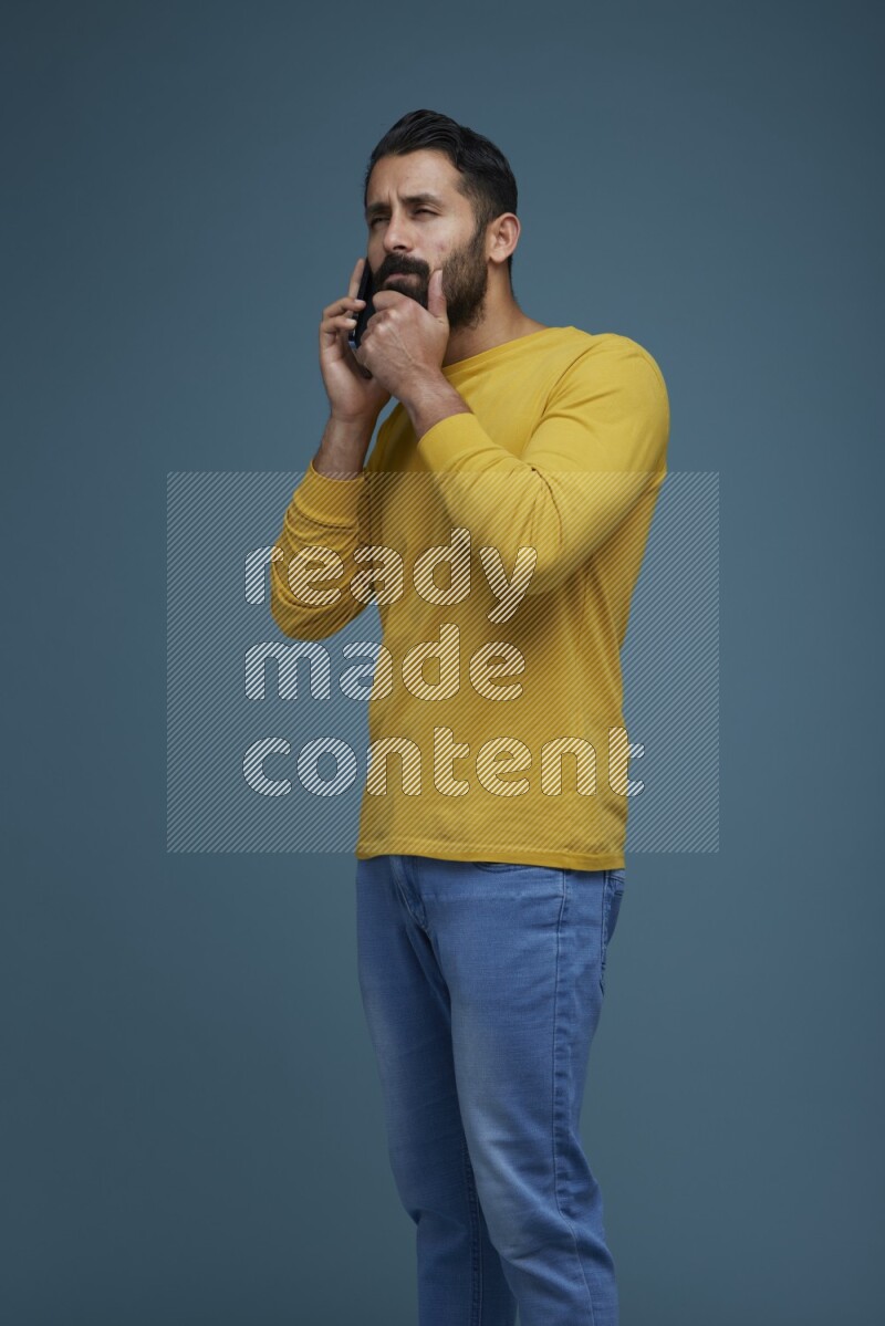 A man having a calling in a blue background wearing a yellow shirt
