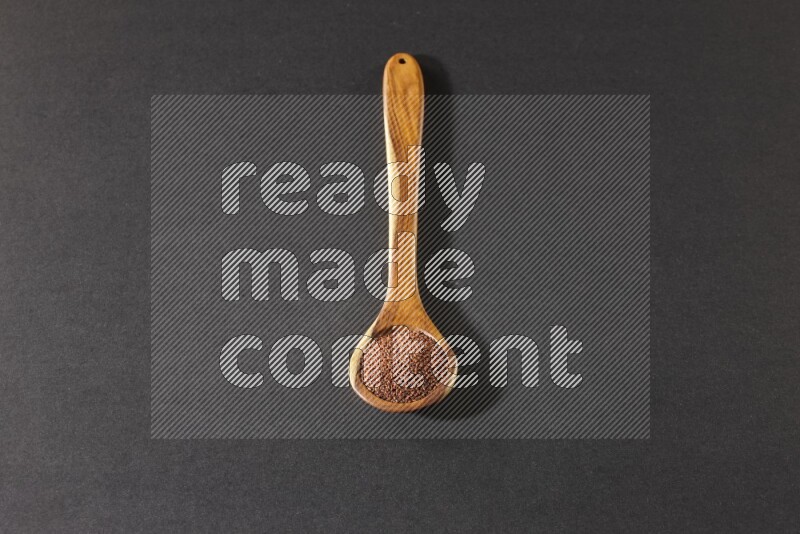 ملعقة خشبية كبيرة ممتلئة ببذور حب الرشاد علي خلفية سوداء