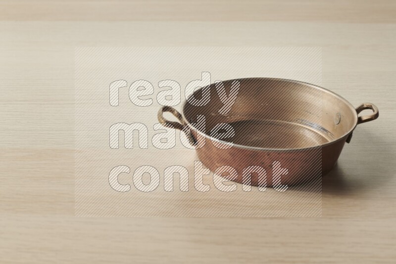A small copper pan on light wooden background