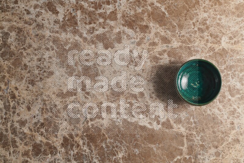 A dark green pottery bowl on beige marble background
