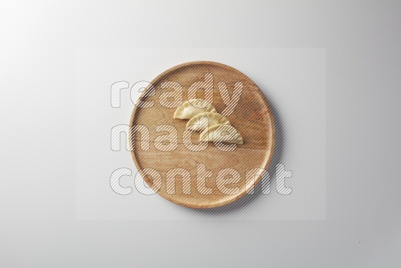 Three Sambosas on a wooden round plate on a white background