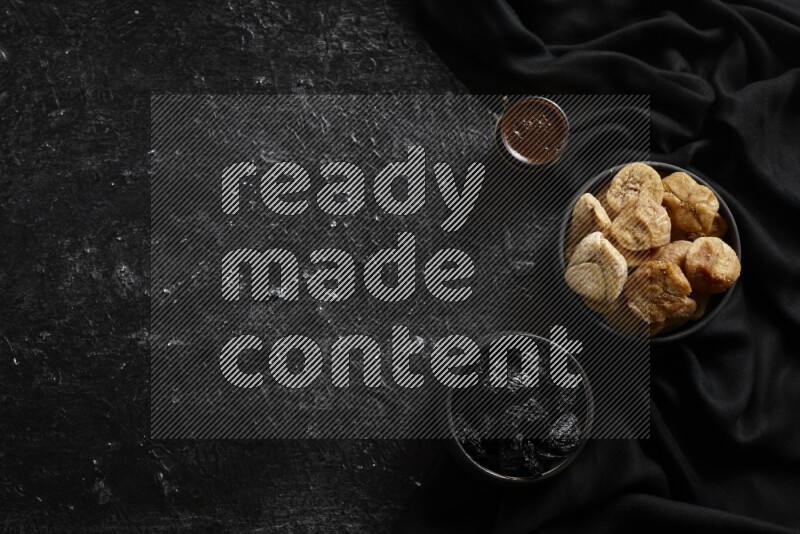 Dried fruits in pottery bowls with coffee in a dark setup