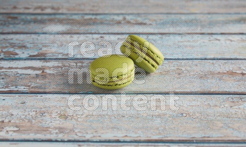 45º Shot of two Green Pistachio macarons on light blue wooden background