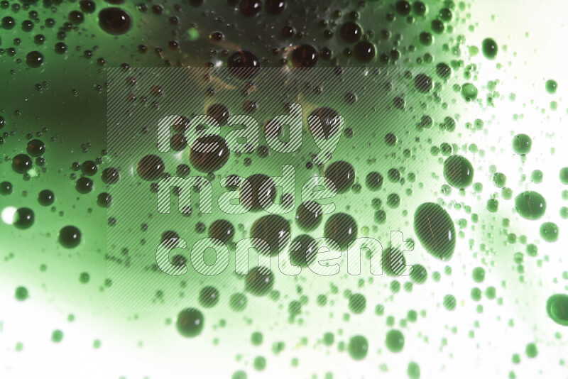 Close-ups of abstract green watercolor drops on oil Surface on white background
