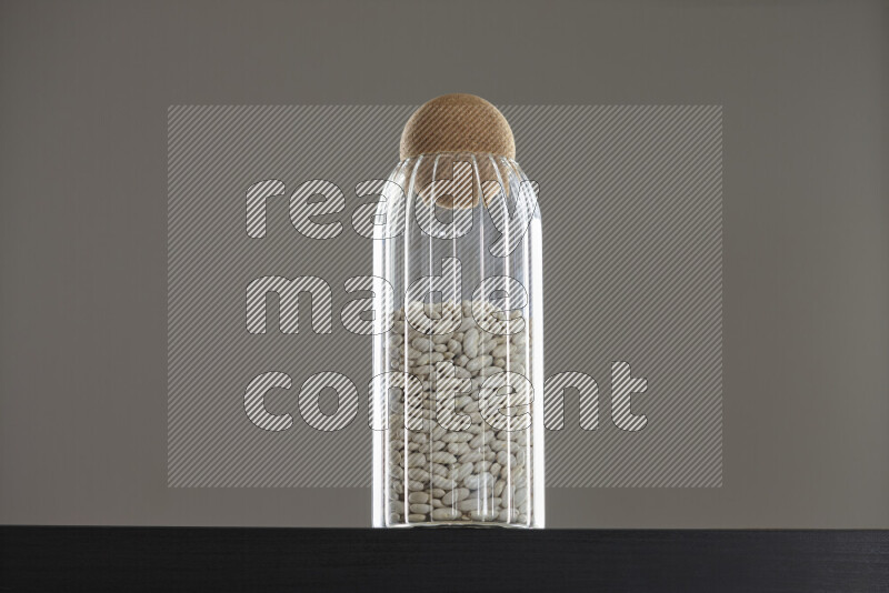 White beans in a glass jar on black background