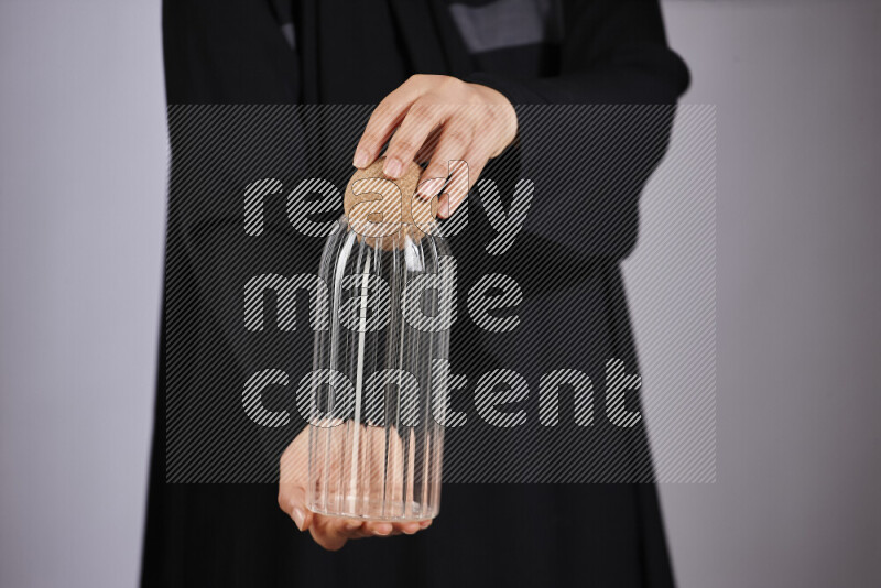 A woman in black abaya holding different glassware in different positions