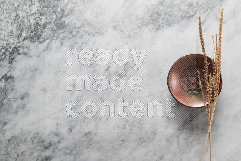 Wheat stalks on decorative pottery plate on grey marble background