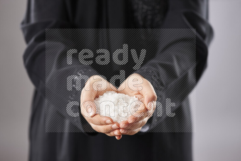 Woman in abaya holding different kinds of spices in different positions