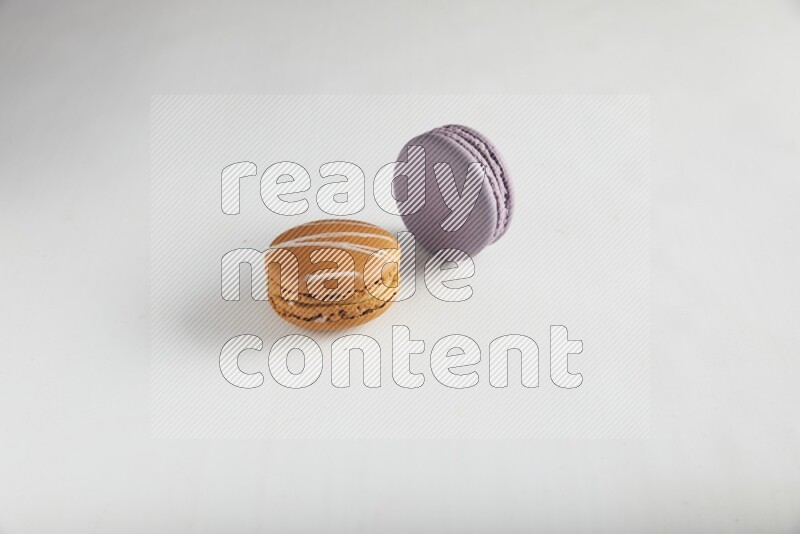 45º Shot of of two assorted Brown Irish Cream, and Purple Blueberry macarons on white background