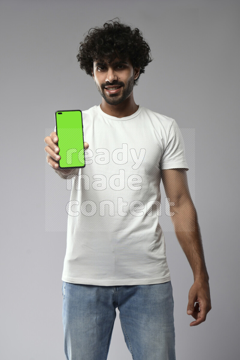 A man wearing casual standing and showing a phone screen on white background