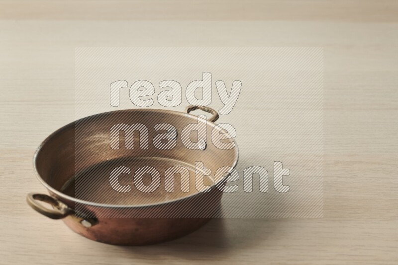 A small copper pan on light wooden background