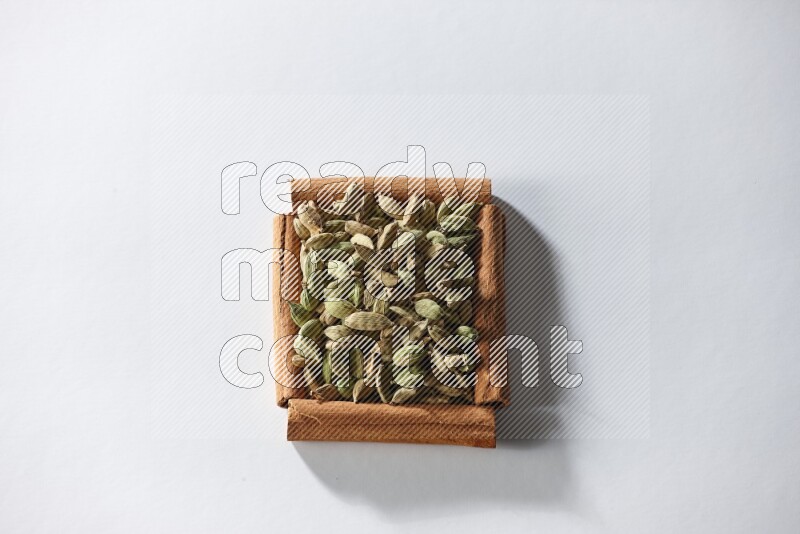 A single square of cinnamon sticks full of cardamom on white flooring