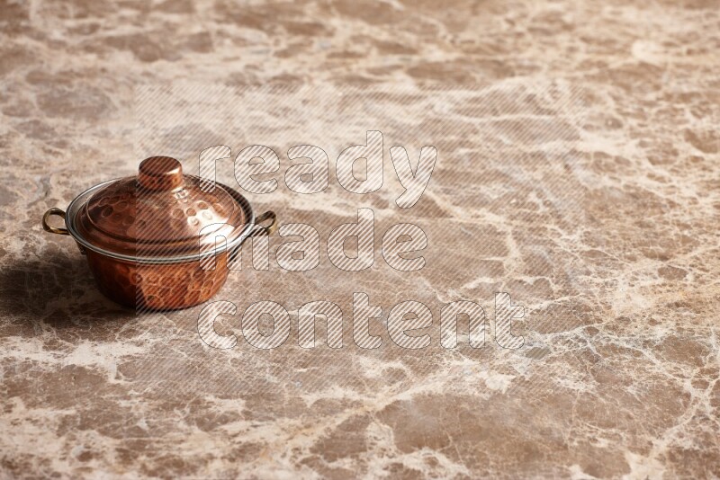 A small copper pot on beige marble background