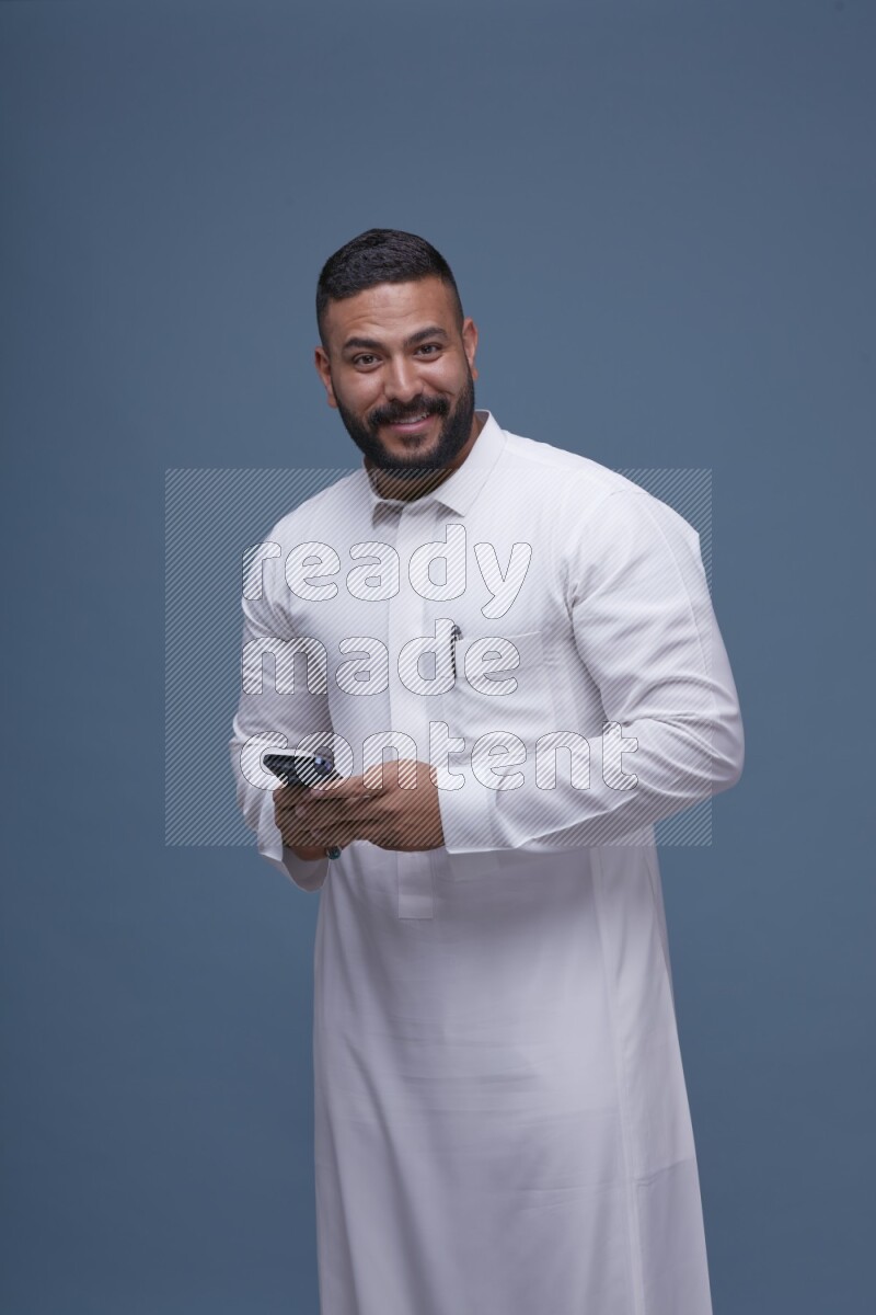 A man Texting on Blue Background wearing Saudi Thob