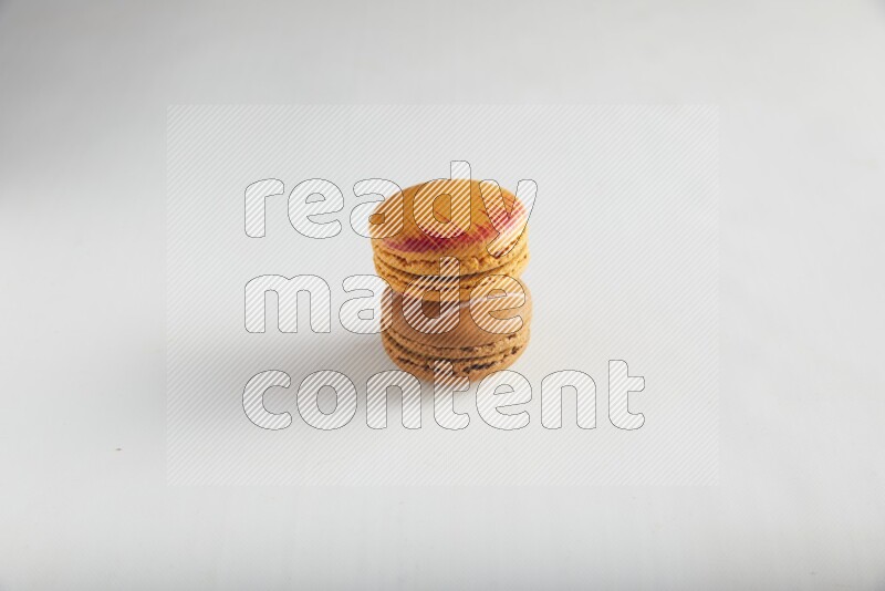 45º Shot of of two assorted Brown Irish Cream, and Orange Exotic macarons on white background