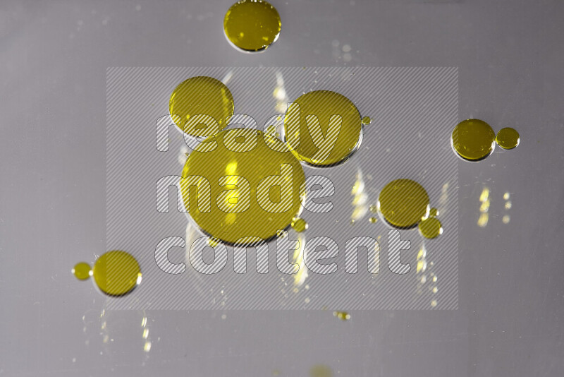 Close-ups of abstract yellow watercolor drops on oil Surface on white background