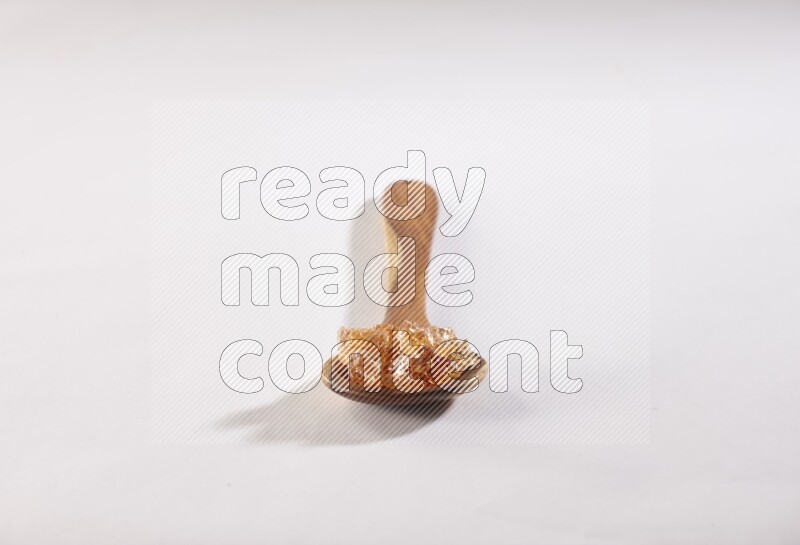 ملعقة خشبية كبيرة ممتلئة بقطع الصمغ العربي علي خلفية بيضاء