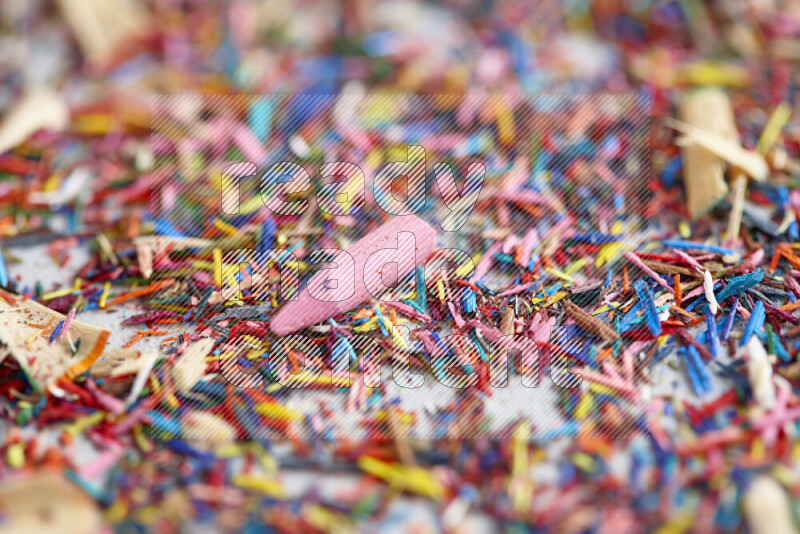 This image showcases a vibrant multicolored pencil shavings scattered on grey background