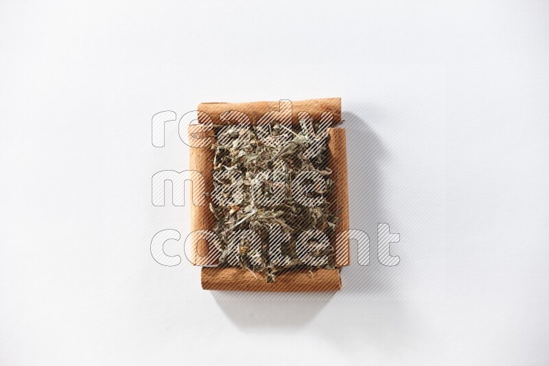 A single square of cinnamon sticks full of dried basil on white flooring