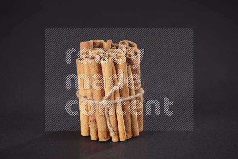 A bounded stack of cinnamon sticks on black background