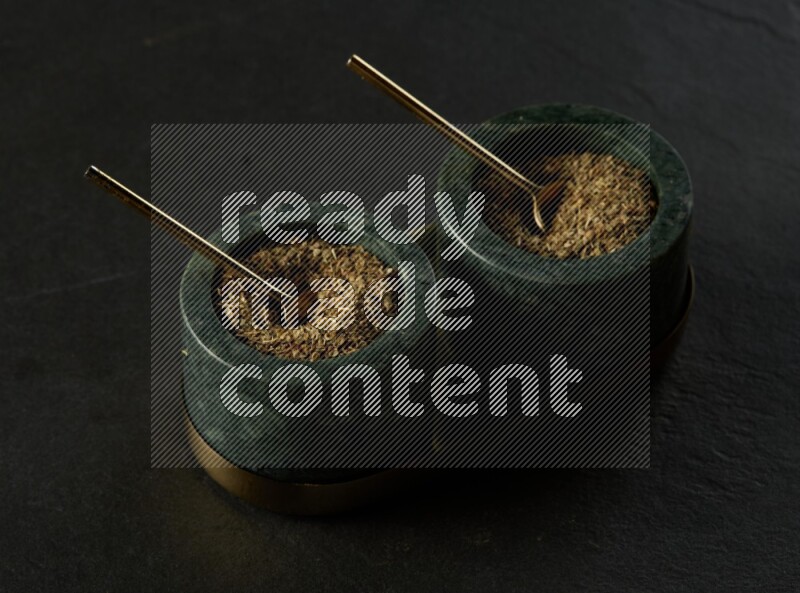 black and white round marble containers filled with herbs on gray textured countertop